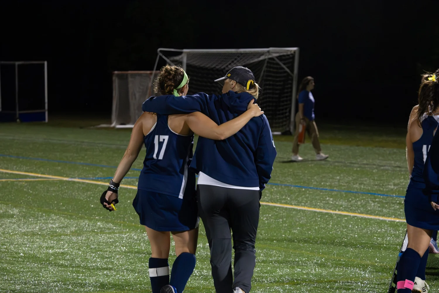 Photo of an Ithaca College field hockey player and coach hugging while walking